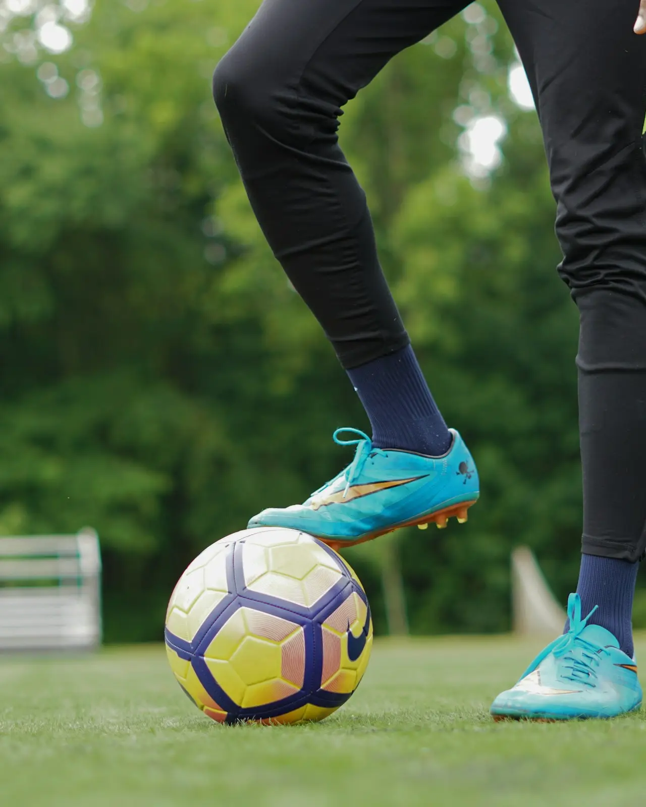 Someone with a foot on the ball on a pitch in the park